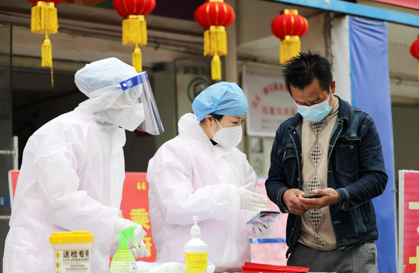 醫(yī)務(wù)工作人員指導(dǎo)返崗務(wù)工人員查尋核酸檢測結(jié)果。