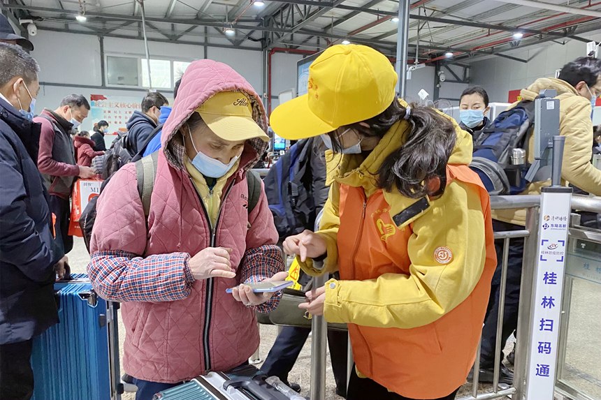 志愿者引導(dǎo)務(wù)工人員掃碼進(jìn)站。陳雨雨攝