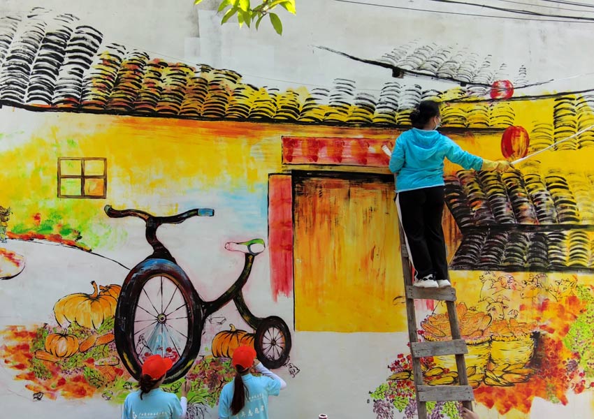 大學(xué)生志愿者繪制鄉(xiāng)村主題墻畫(huà)。