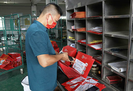 中國(guó)郵政百色市分公司工作人員正在分揀百色學(xué)院2022級(jí)新生的錄取通知書 王士嘉 攝