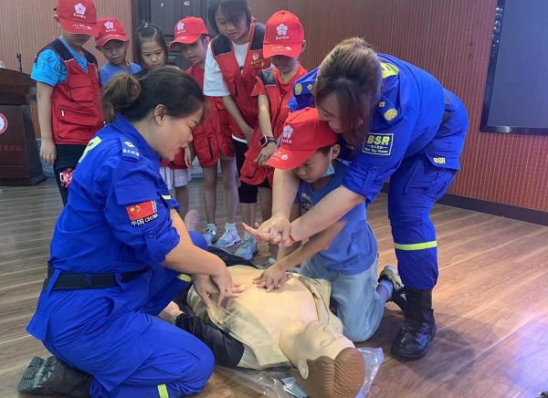 廖雯(右一)和周喜雄(左一)手把手教孩子做心肺復(fù)蘇。