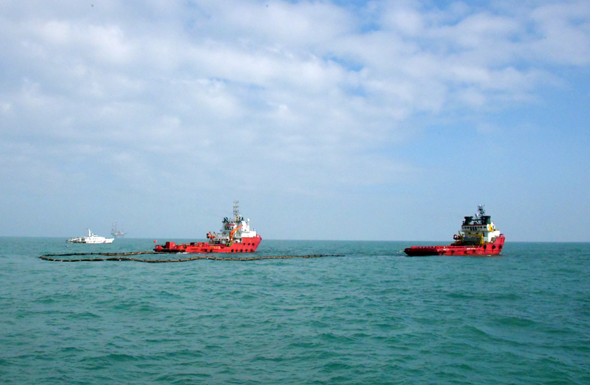 拖輪進(jìn)行溢油圍控回收作業(yè)。