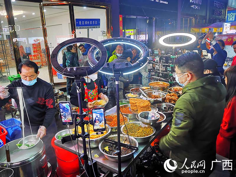 市民游客在柳州一家螺螄粉攤前排隊嗦粉。人民網(wǎng) 付華周攝