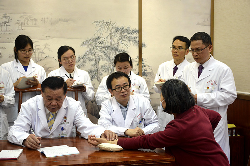 黃瑾明（左一）為患者把脈。馮興勝攝