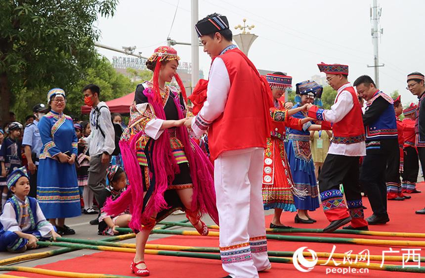 同時(shí)，場地另一頭，一陣陣鏗鏘有力、節(jié)奏明快的響聲傳來，來自壯族、漢族、瑤族等不同民族的男女老少身著盛裝，跳起竹竿舞。人民網(wǎng)記者 彭遠(yuǎn)賀攝