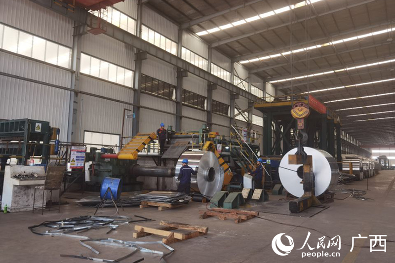 在潤(rùn)泰鋁業(yè)的生產(chǎn)車間，工人正將鋁卷放入機(jī)器進(jìn)一步加工。人民網(wǎng) 覃心攝