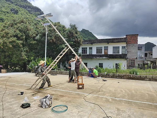 大龍村板外屯群眾給球場豎桿、拉線安裝燈光。潘璠攝