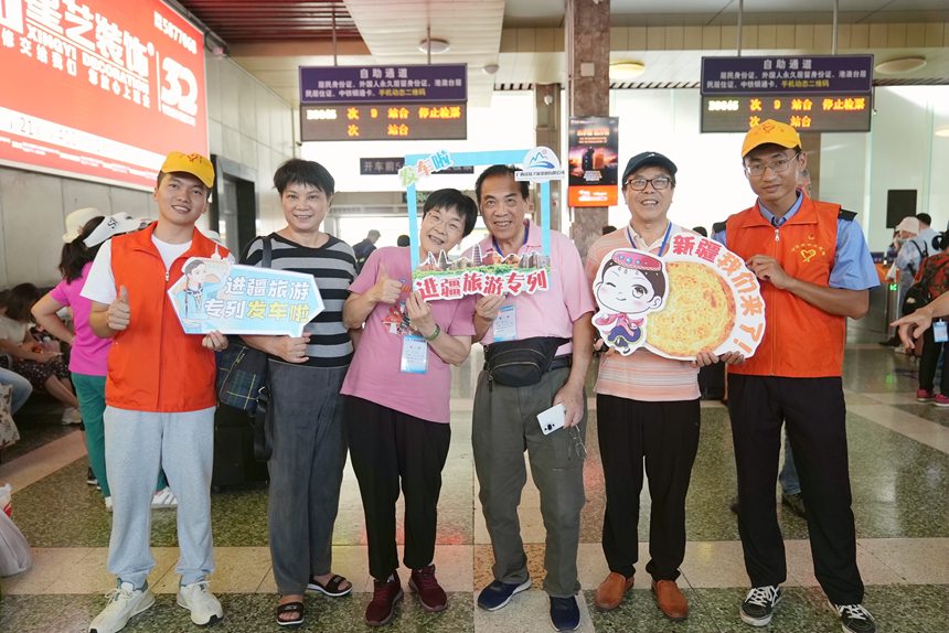 鐵路志愿者與乘坐“進疆旅游專列”的乘客在候車室合影。蘭軻艨攝