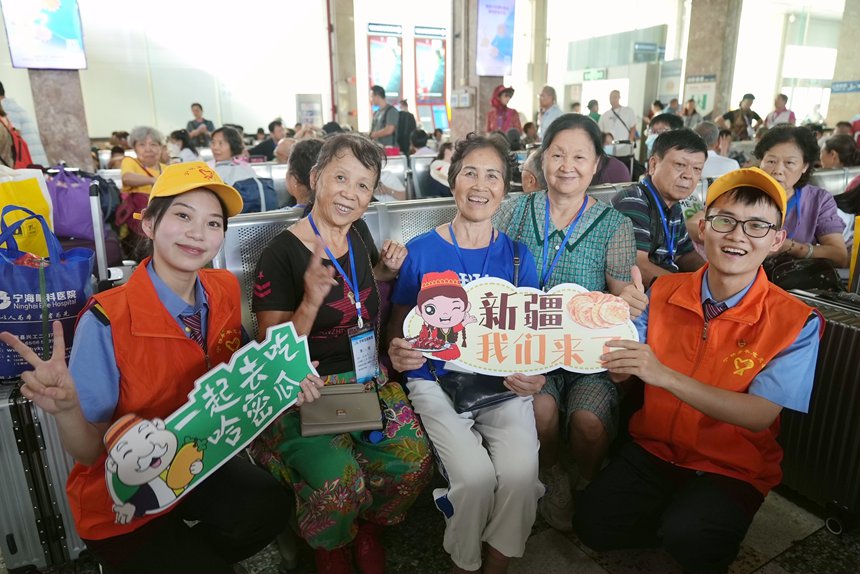 鐵路志愿者與“進(jìn)疆旅游專列”的乘客在候車室合影。何毅攝