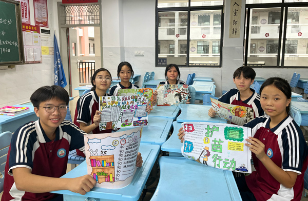 學(xué)生展示自己設(shè)計的“掃黃打非”板報作品。