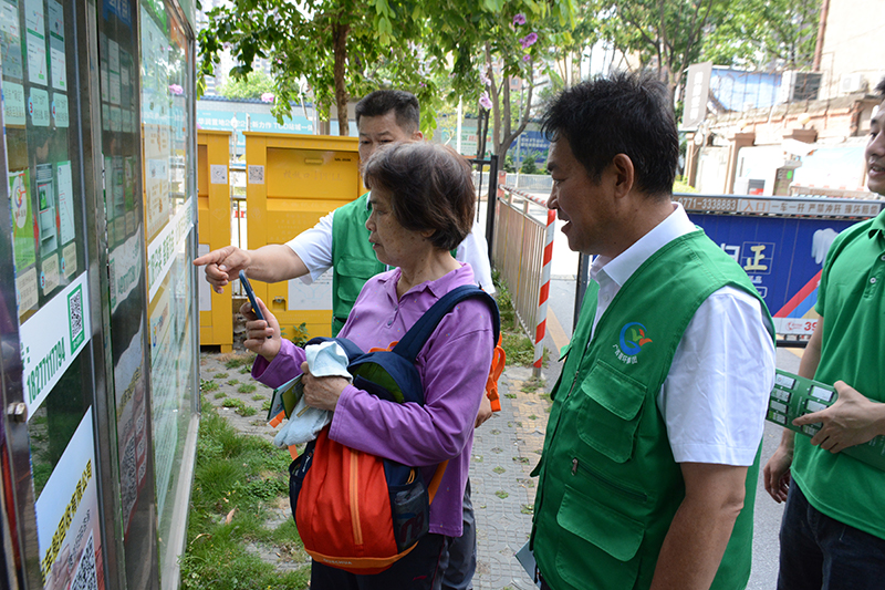 工作人員指導(dǎo)社區(qū)居民使用廢舊物資自助投放系統(tǒng)。廣西桂物再生資源有限公司供圖