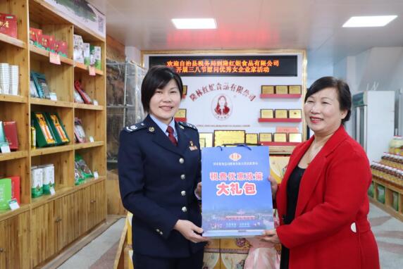 圖為隆林各族自治縣稅務(wù)局黨委書記、局長譚凌聆為隆林紅姐食品有限公司負責人李紅送上稅費優(yōu)惠政策大禮包。張蕾蕾攝