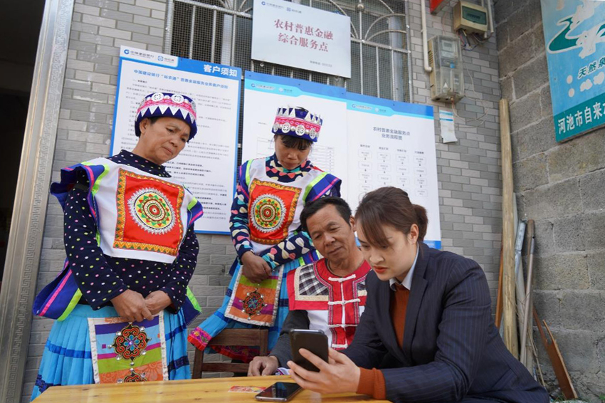 客戶經(jīng)理向村民講解如何使用“裕農(nóng)通”。建行宜州支行供圖