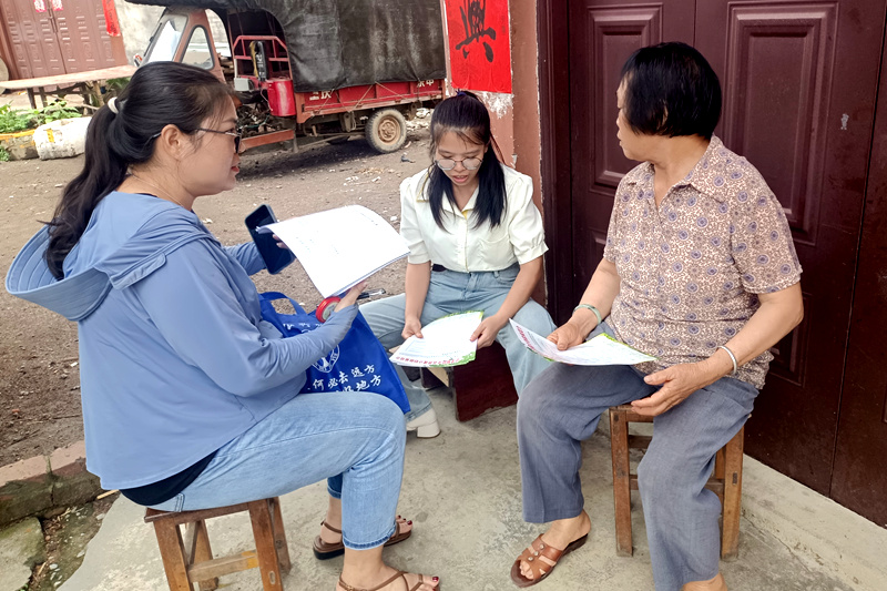 黃其艷（中間）與同事進(jìn)村入戶講政策。
