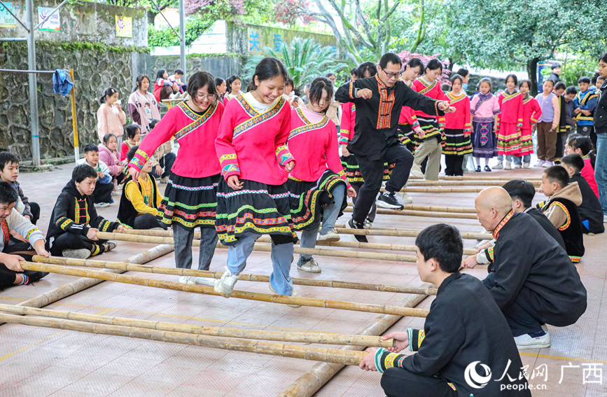 瑤鄉(xiāng)的老師和學(xué)生們身著民族服飾跳竹竿舞。人民網(wǎng)記者 陳燕攝