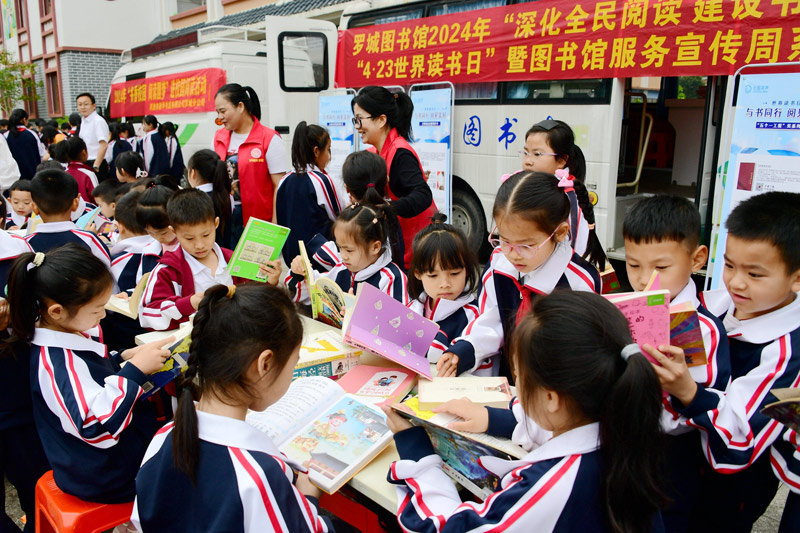 小學(xué)生在流動圖書車前閱讀圖書。