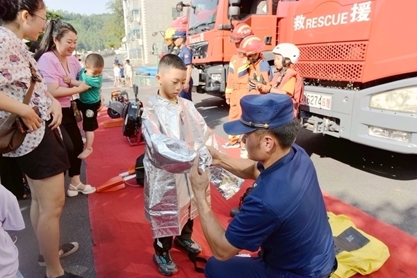 消防員給孩子們試穿消防服。