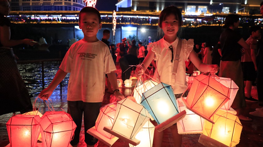 游客拿著河燈漂放。
