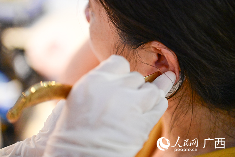 南寧市中醫(yī)醫(yī)院醫(yī)務人員為市民進行耳部全息虎符銅砭刮痧。人民網(wǎng) 雷琦竣攝