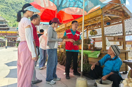 浩坤村第一書記李萬華在浩坤湖景區(qū)碼頭幫農(nóng)戶推銷農(nóng)特產(chǎn)品。凌云縣委宣傳部供圖