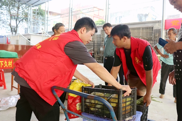 青年志愿者協(xié)助農(nóng)戶擺攤。