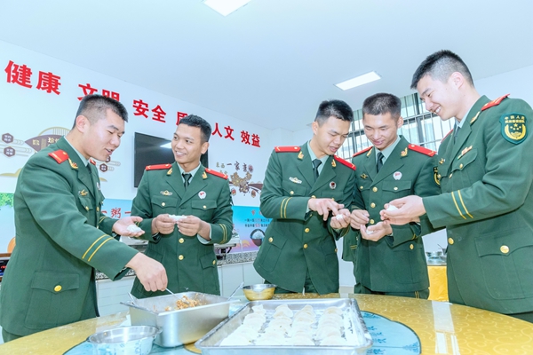 武警官兵相互交流包餃子方法。