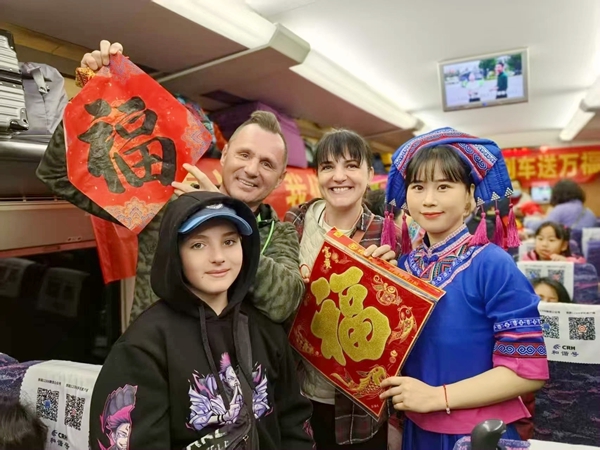 圖為列車長(zhǎng)陳微給乘車的外籍旅客送福，并合影留念。劉媛 攝