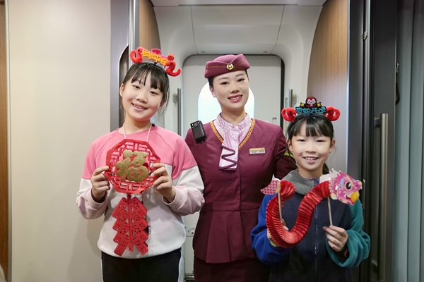 圖為列車長楊亞楠給乘車的孩子贈送福字、玩偶，并合影留念。曹爍攝