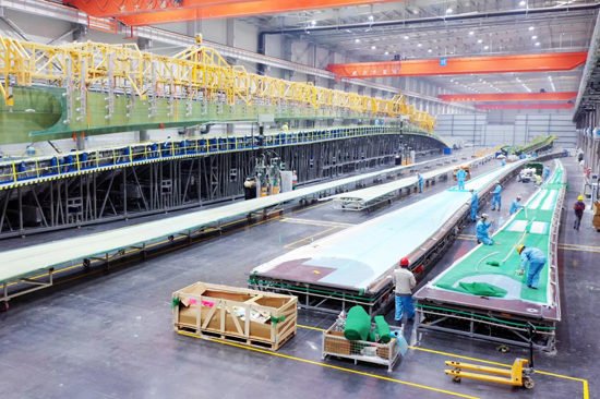 中車百色新能源裝備產(chǎn)業(yè)項(xiàng)目葉片生產(chǎn)車間，工人在生產(chǎn)線上忙碌的檢查設(shè)備。