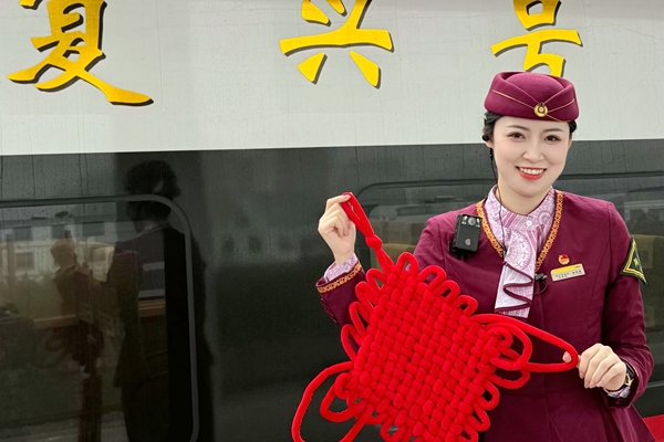 姜喜嘉在復(fù)興號(hào)前拿著中國結(jié)，為開展列車活動(dòng)做準(zhǔn)備。徐祖萍攝