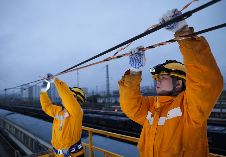 接觸網(wǎng)工正在為百色普速場(chǎng)的接觸網(wǎng)承力索安裝預(yù)絞式保護(hù)條。韋杰攝