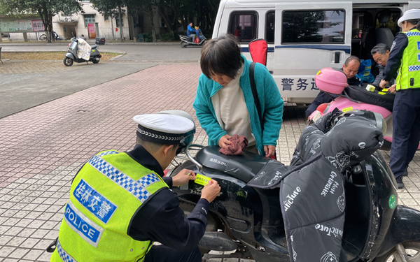 交警在日常巡邏過程中為群眾張貼反光貼。桂林市公安局供圖