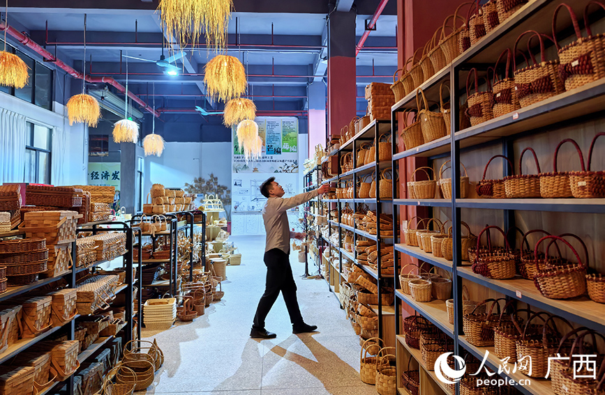 莫思明查看企業(yè)生產的非遺工藝品。人民網 付華周攝