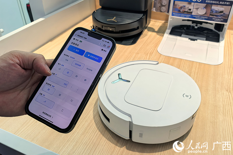導(dǎo)購小陳用手機(jī)操控掃地機(jī)器人。人民網(wǎng)記者 覃心攝