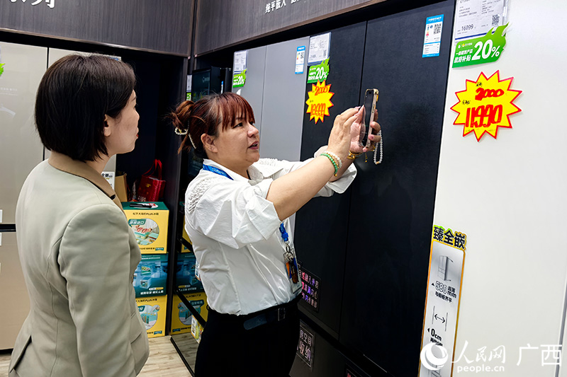 商場導(dǎo)購員向消費(fèi)者介紹智能冰箱。人民網(wǎng)記者 覃心攝