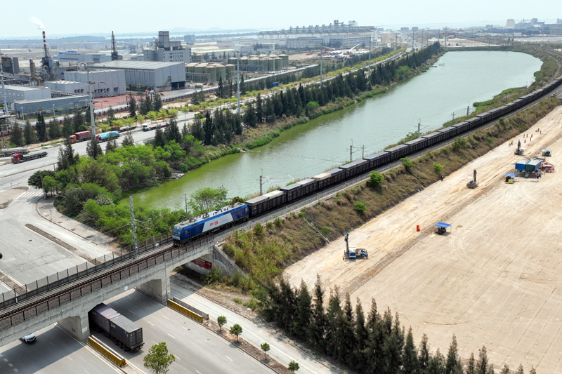 圖為一趟滿(mǎn)載集裝箱貨物的西部陸海新通道鐵海聯(lián)運(yùn)班列，從欽州港東站緩緩駛出。何家海攝