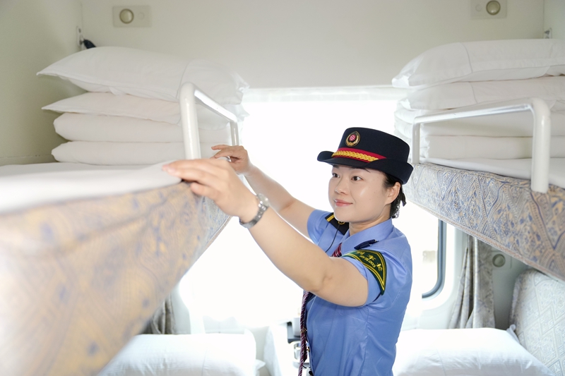 中越國(guó)際旅客列車(chē)列車(chē)長(zhǎng)蘭秋霜整理臥鋪臥具。曹爍攝