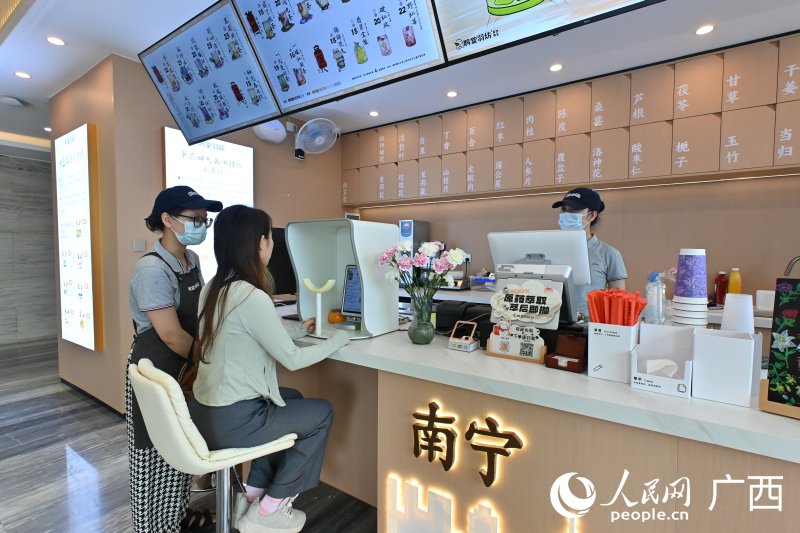 韋女士在店員的指導(dǎo)下使用AI配制中藥茶飲。人民網(wǎng) 雷琦竣攝