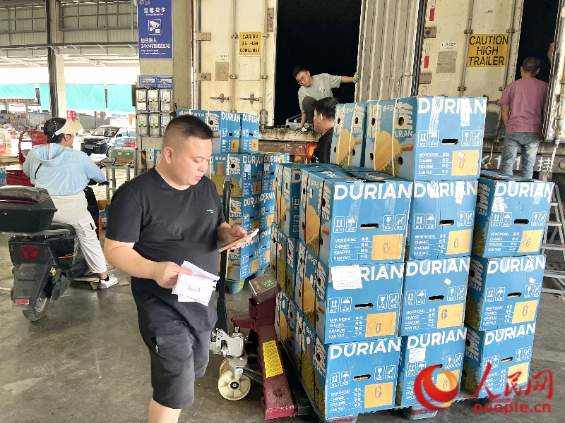 鄧清遠(yuǎn)右手拿著客單，左手飛速敲擊手機(jī)屏幕與采購(gòu)商溝通。人民網(wǎng) 韋歡攝