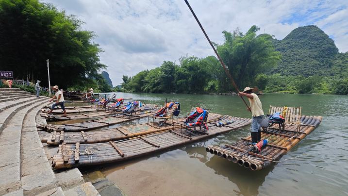 行進(jìn)中國(guó)丨遇龍河上，“智慧筏”撐開(kāi)新景中午12點(diǎn)，桂林市陽(yáng)朔縣遇龍河景區(qū)筏工蔣受乾將竹筏?？吭隗K馬碼頭旁，仔細(xì)擦拭竹筏上的座椅。隨著游客登筏，他的服務(wù)里程、安全記錄與游客評(píng)價(jià)，都將通過(guò)無(wú)形的數(shù)據(jù)，實(shí)時(shí)匯入景區(qū)“智慧大腦”的江河。