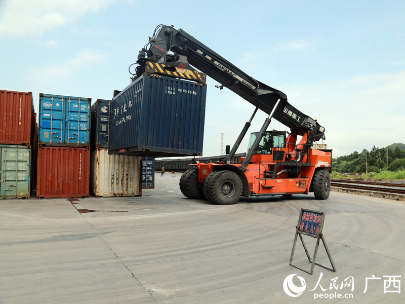 鐘山站貨場(chǎng)內(nèi)，正面吊在吊裝石料集裝箱。