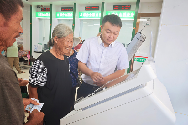 工作人員幫助老人操作“社銀服務(wù)一體機(jī)”。黃民攝