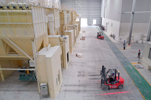 廣西隆升新材料有限公司生產(chǎn)車間內(nèi)，工人使用機(jī)械臂搬運(yùn)碳酸鈣粉體產(chǎn)品。