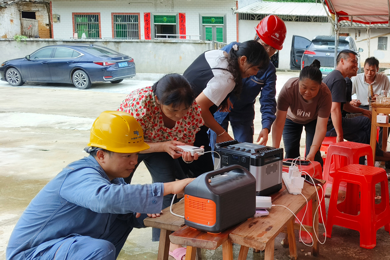 10月6日，陸川供電局大橋供電所第一時間組織客戶服務(wù)班人員前往10千伏街Ⅰ線王沙公變停電區(qū)域，用便攜式充電設(shè)備及時為村民提供手機(jī)充電服務(wù)。大橋供電所供圖