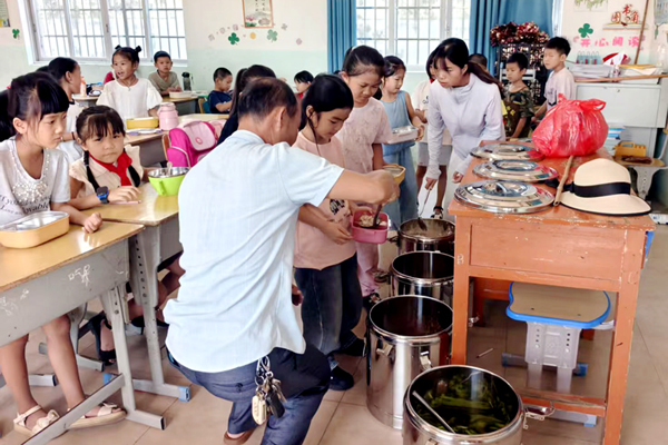 老師幫學(xué)生裝營養(yǎng)午餐。