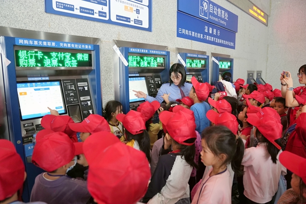鐵路職工在玉林站售票廳給研學(xué)學(xué)生講解自助售票操作流程。何毅攝