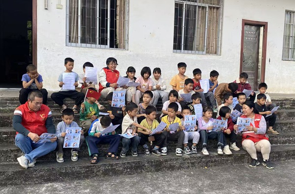 黨員志愿者與學(xué)生共同學(xué)習(xí)安全用火用電手冊(cè)。廣西大錳集團(tuán)供圖