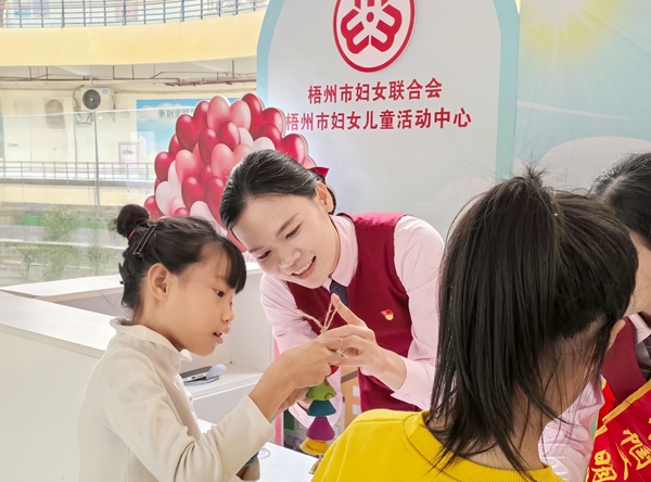 工作人員教小朋友制作手工風(fēng)鈴。