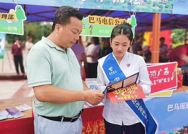 河池巴馬縣舉辦中國(guó)旅游日主題活動(dòng)，中國(guó)電信工作人員在現(xiàn)場(chǎng)開(kāi)展文旅+反詐融合宣傳。